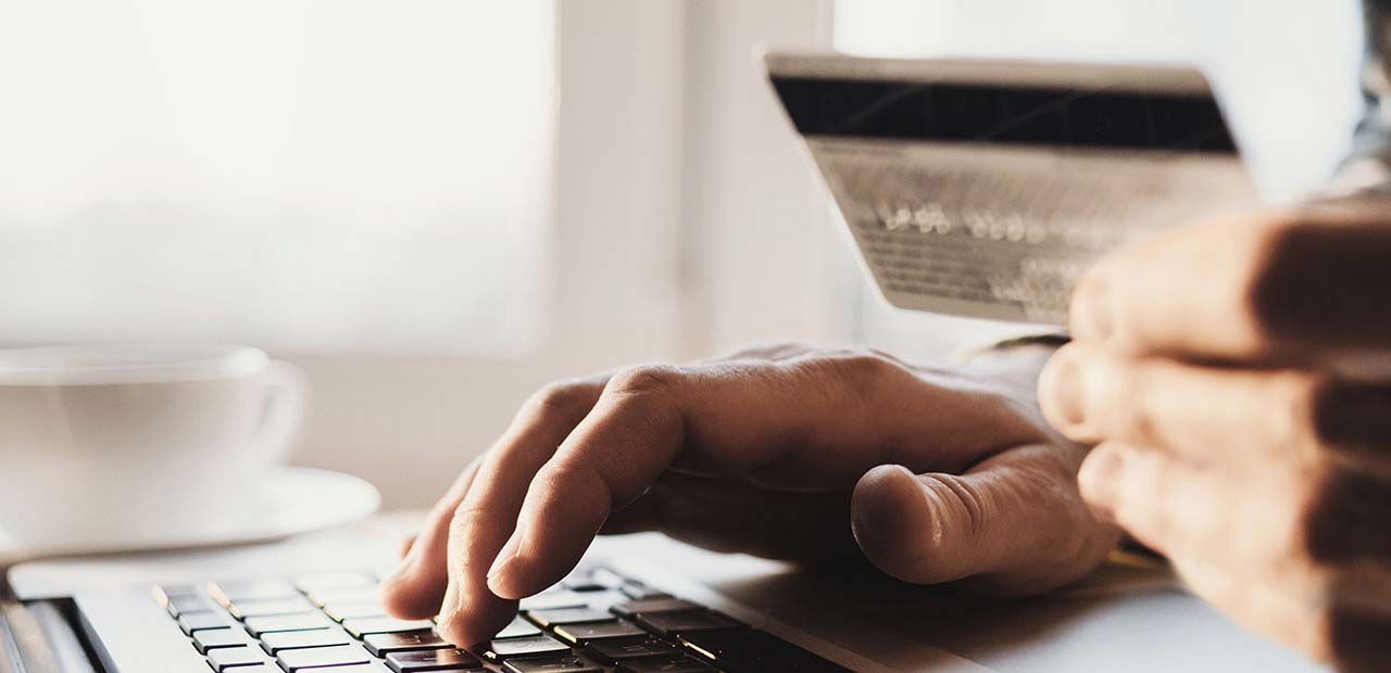 Closeup of man holding a credit card on his laptop